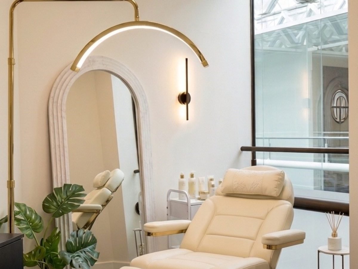 The BKM Aesthetics treatment room in Nottingham, with a cream treatment chair, arched mirror and brass lighting